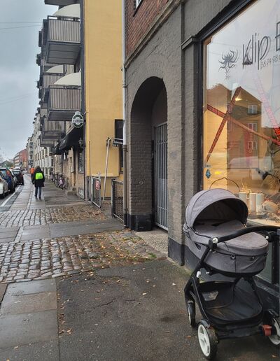 Barnevogn stillet på fortovet uden for en frisør