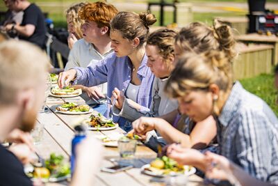 Unge spiser udendørs ved langbord