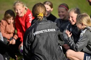 Piger og deres træner sidder i rundkreds udendørs